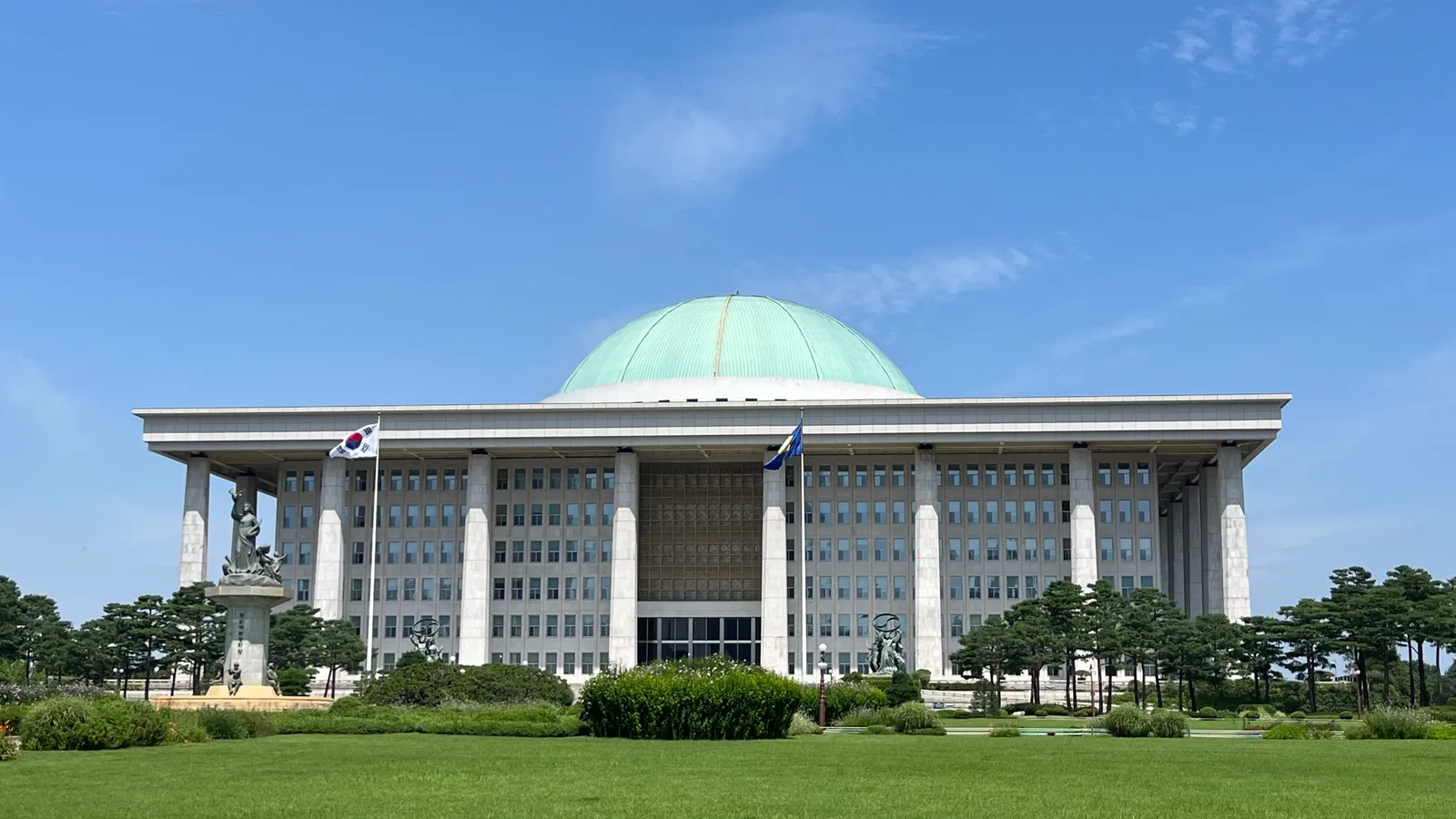 맑은 하늘 아래 잔디밭 너머로 보이는 대한민국 국회의사당 건물
