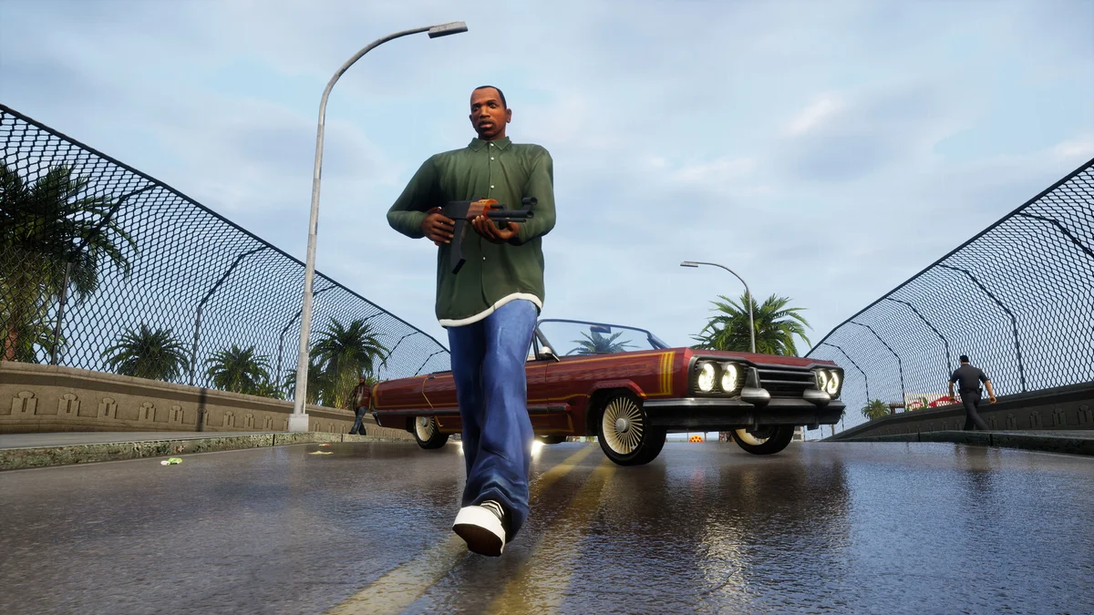 GTA 산 안드레아스 디피니티브 에디션 게임 화면, 캐릭터가 야자수가 늘어선 도로에서 총을 든 채 걸어가는 장면